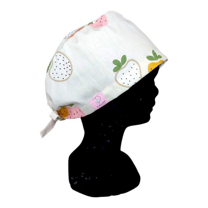 avec ses fraises blanches et roses aux contours dorés sur un fond clair, ce calot apporte une touche